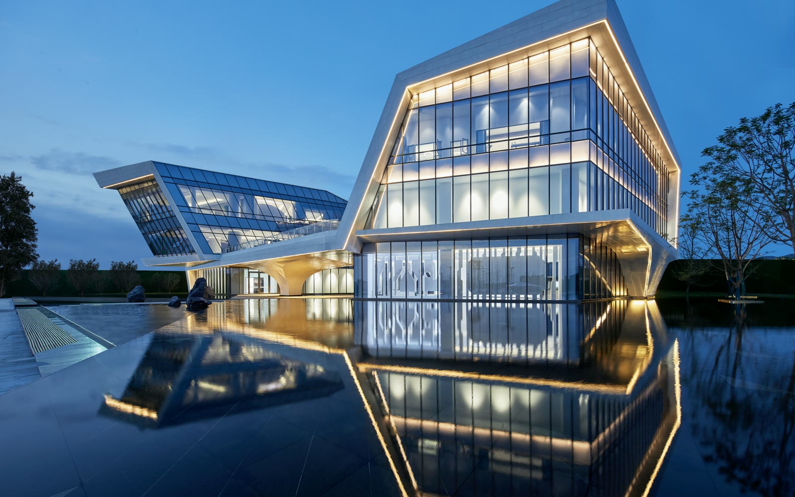 A corporate campus at blue hour mirrored in a reflecting pool