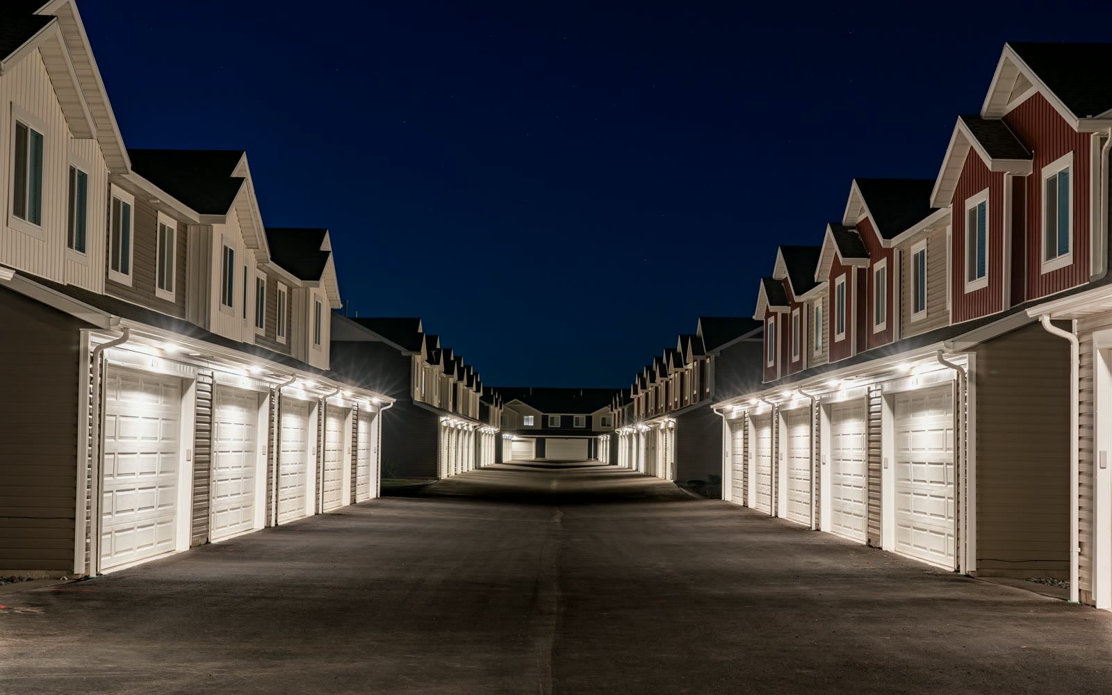 A lit drive between rows of new townhomes at night