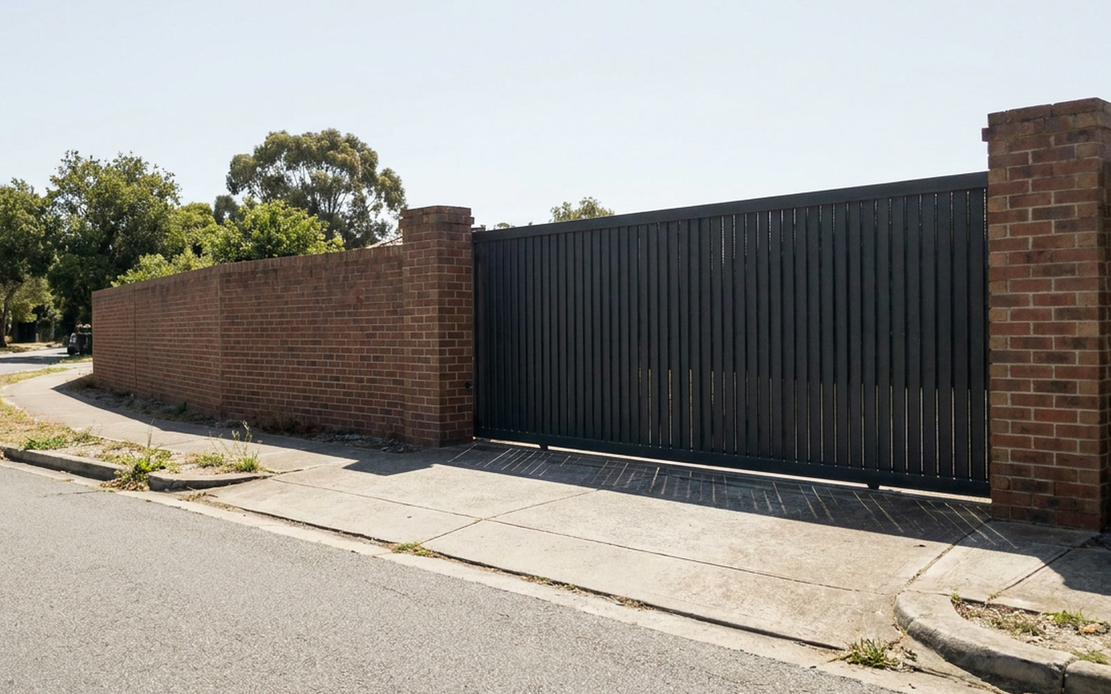 The gated vehicle entrance to a residential street, photographed from the kerb